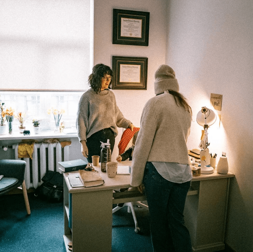 Amanda stands at her desk visiting with a youth